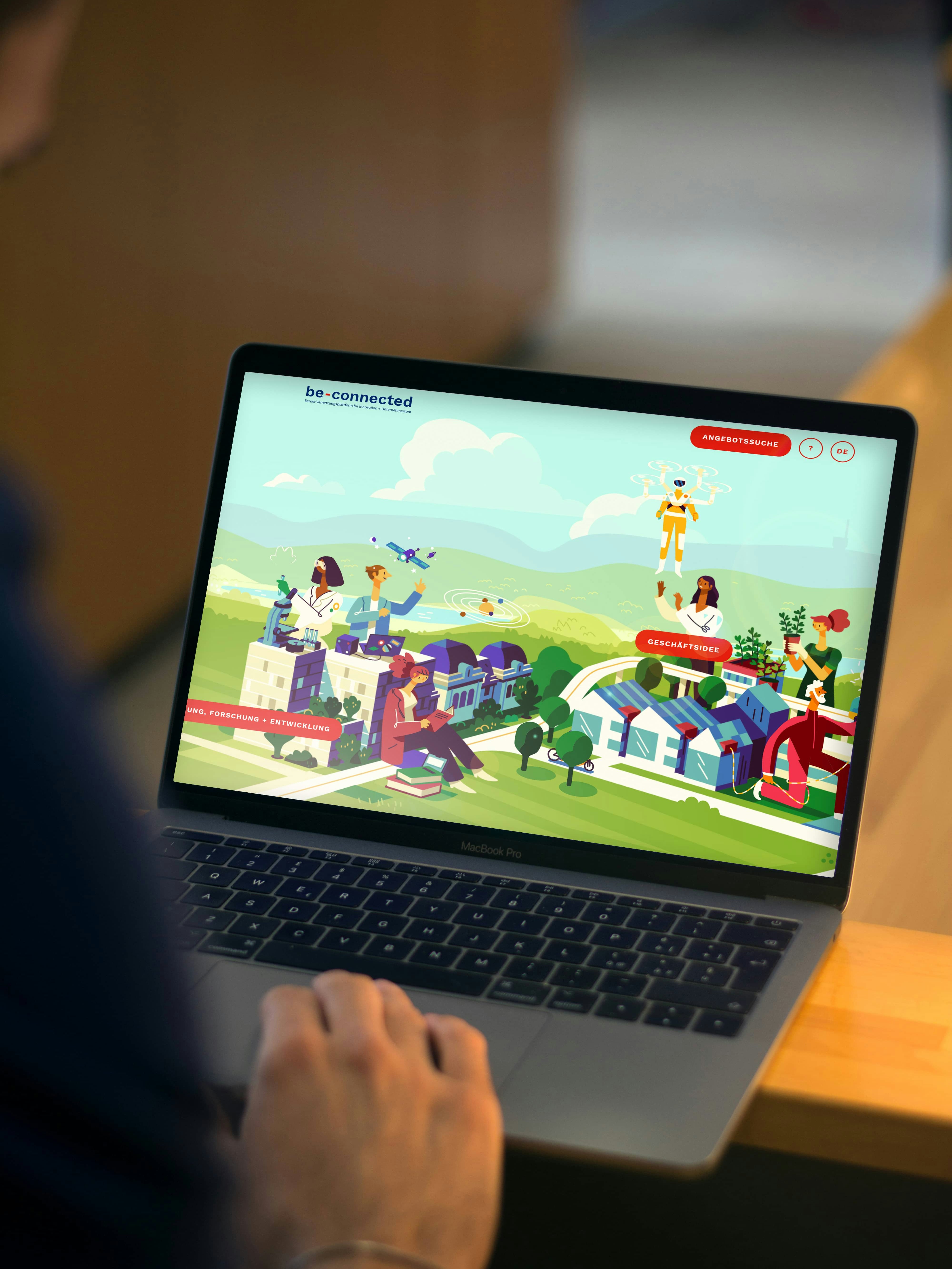 Person using a laptop displaying a webpage with colorful illustrations of people, buildings, and nature, featuring "be-connected" at the top.