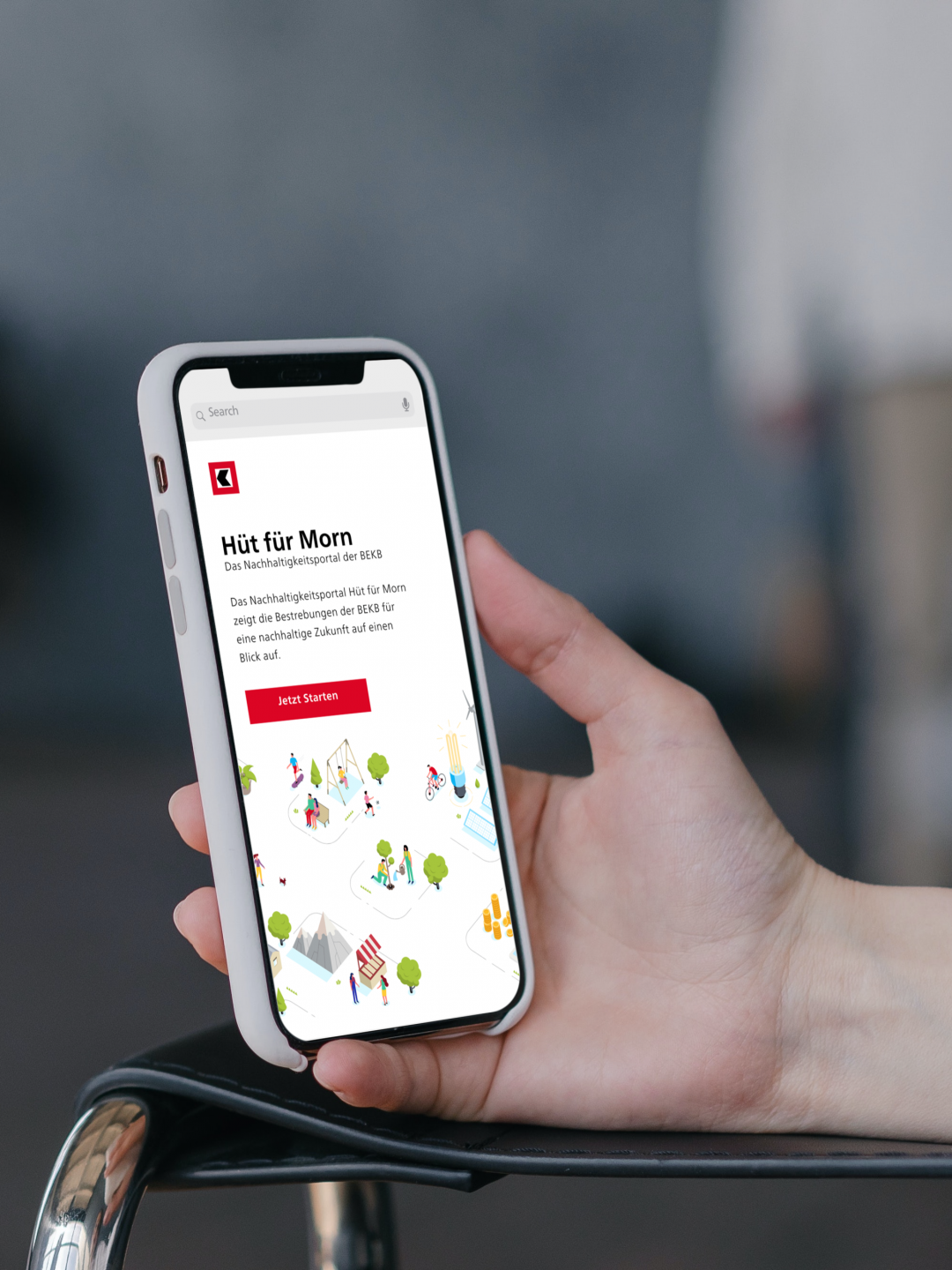 A hand holds a smartphone displaying a website titled "Hit für Morn" in German, featuring a colorful illustration of people and buildings, with a red button labeled "Jetzt Termin.