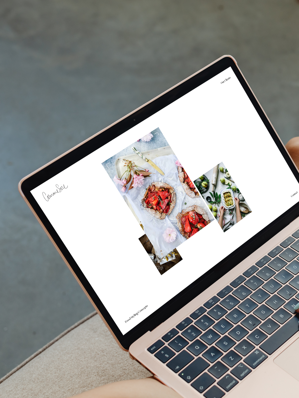 A laptop screen displays a website with images of food, including a fruit tart, surrounded by ingredients and kitchen items.