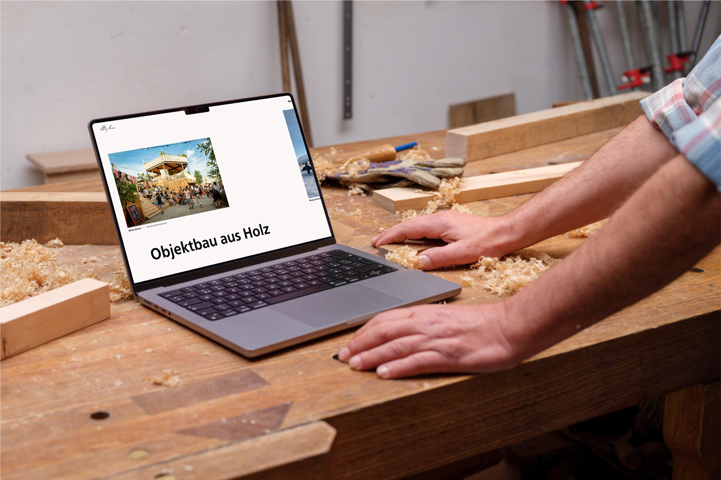 A person working at a wooden table with a laptop displaying an article titled "Objektbau aus Holz," featuring an image of a building.