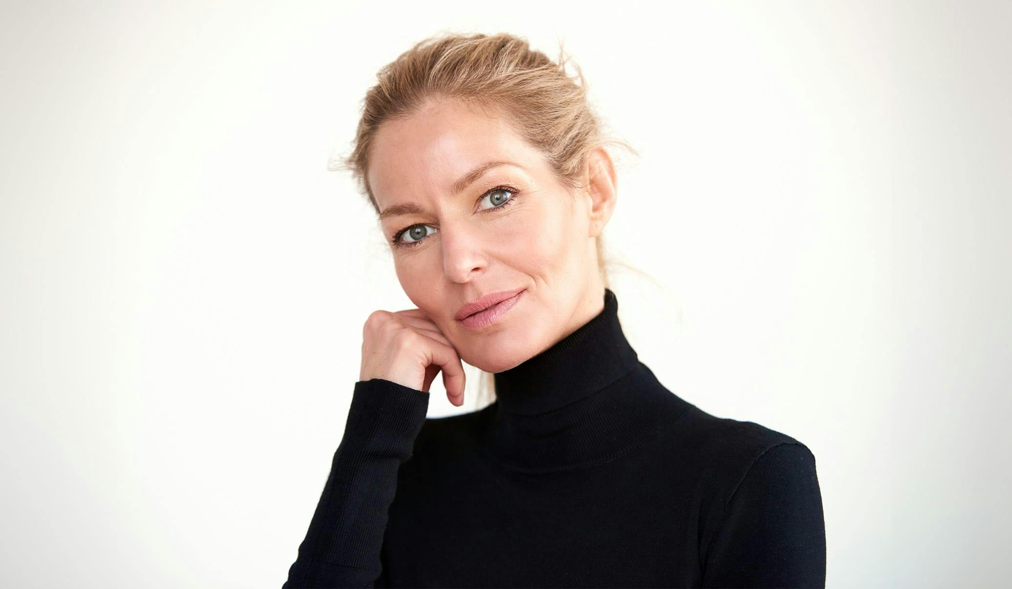 woman with blonde slicked back while wearing a black turtleneck