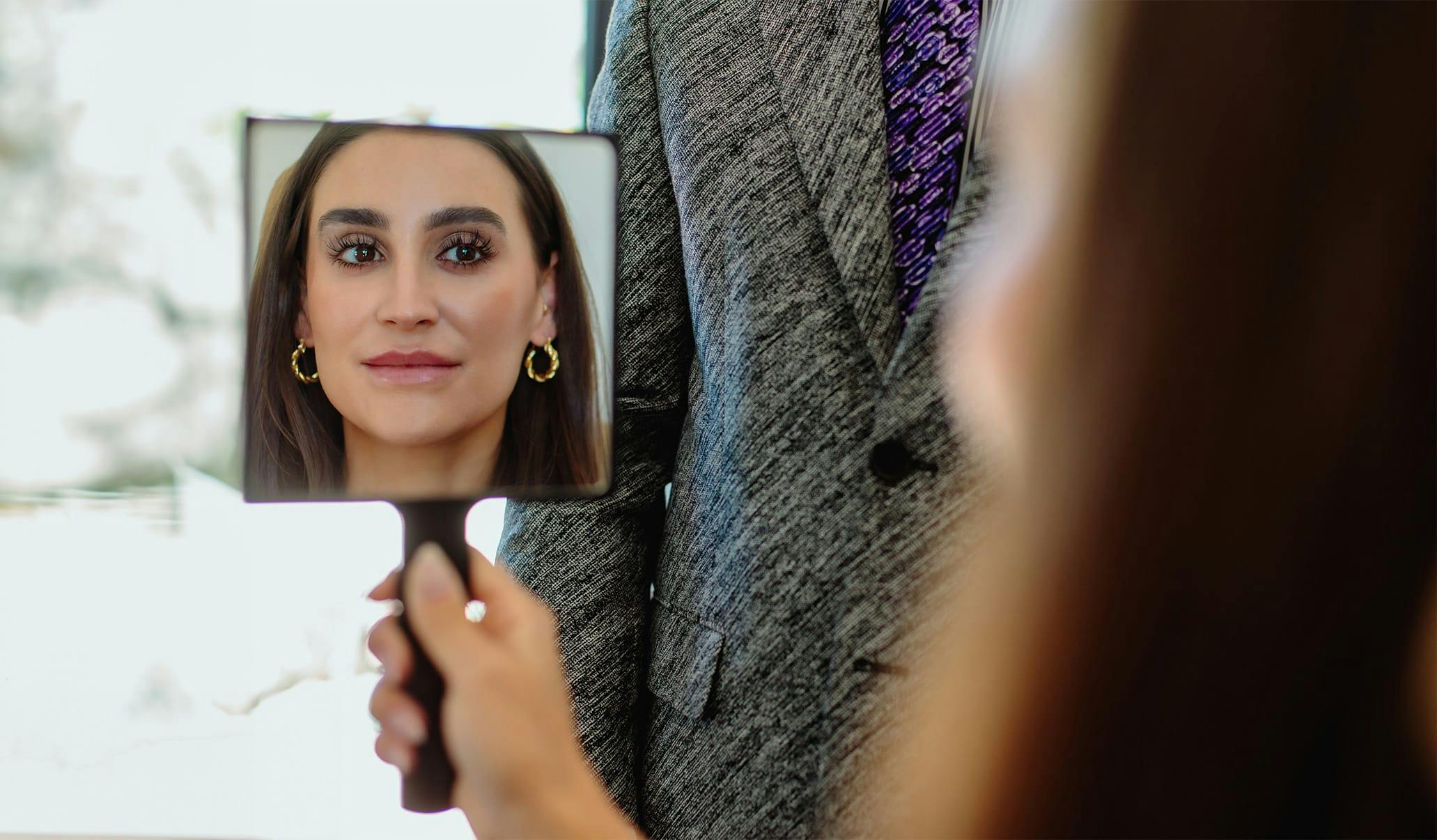 woman looking at herself in a hand mirror