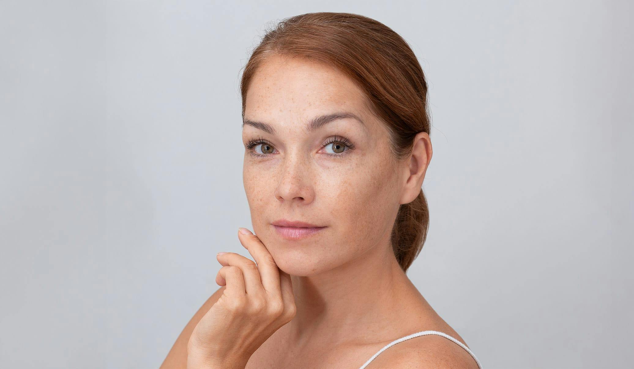 woman with freckles with her hair pulled back