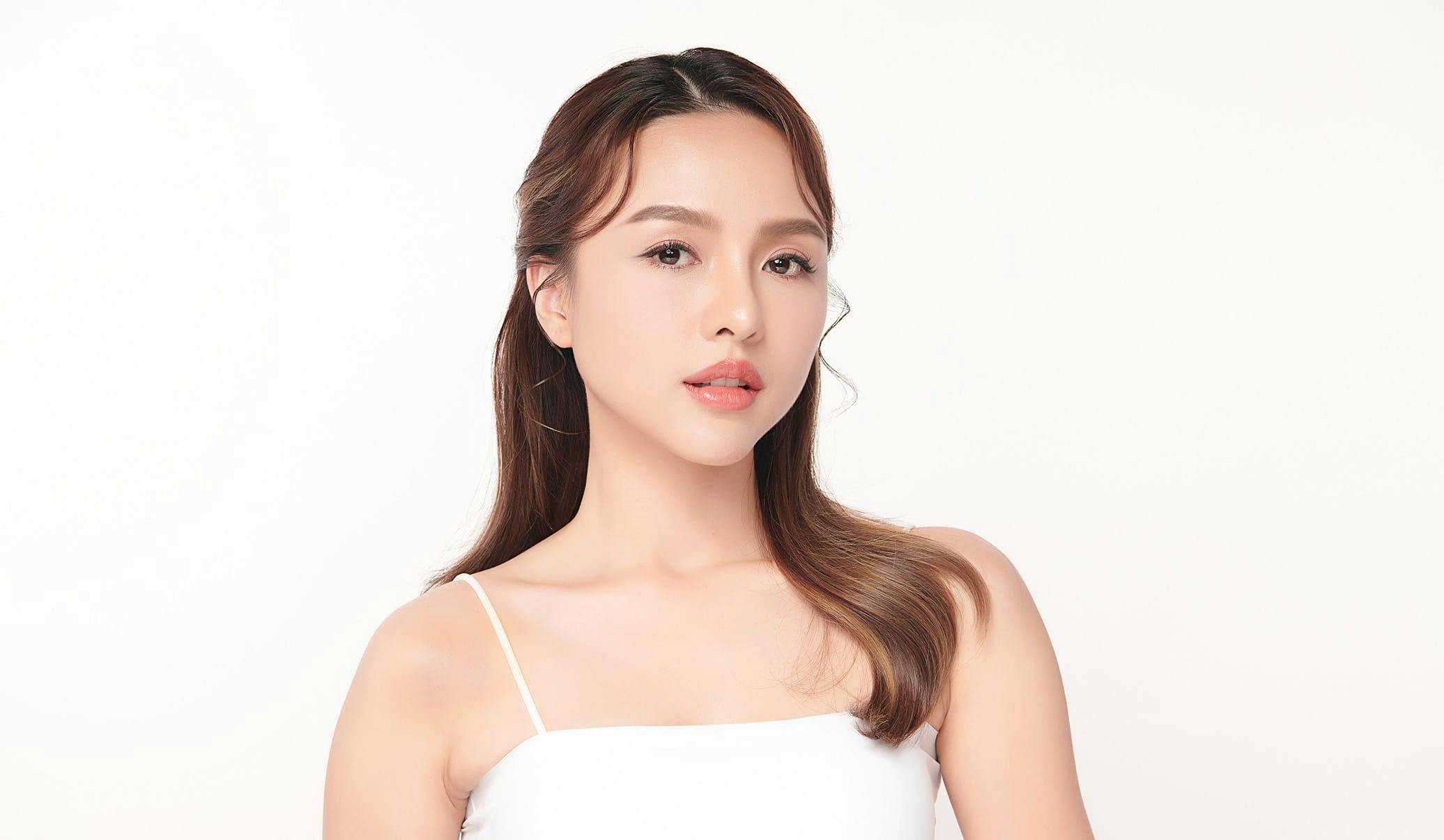woman with brown hair wearing a white top