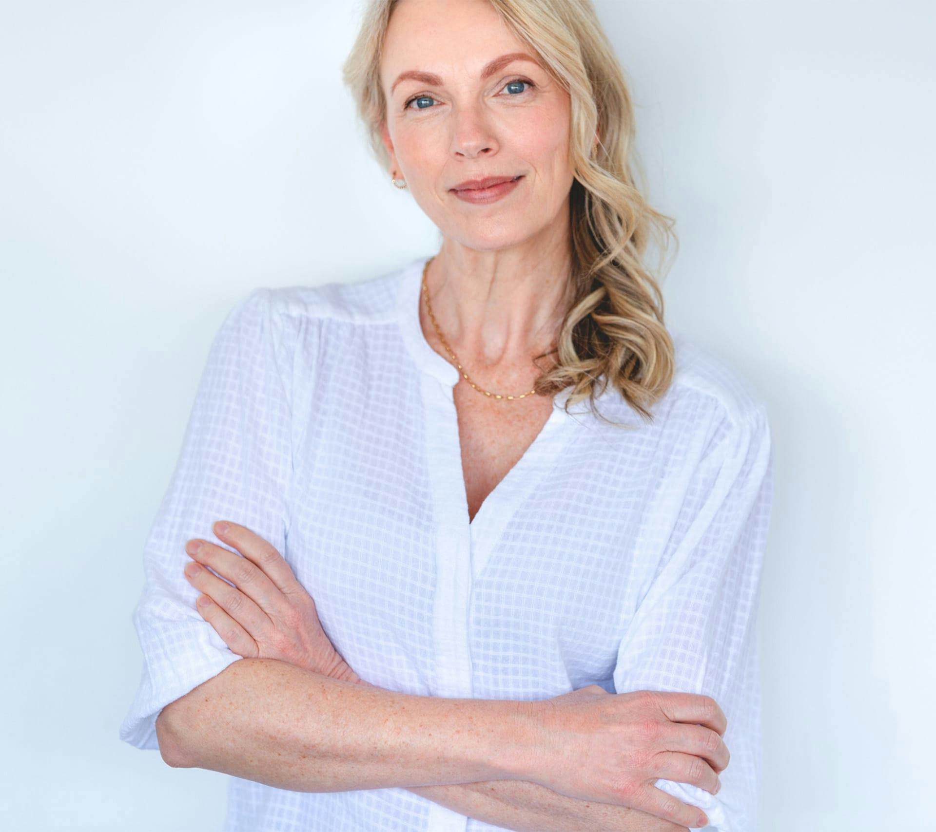woman with blonde curly hair wearing a long-sleeve white top