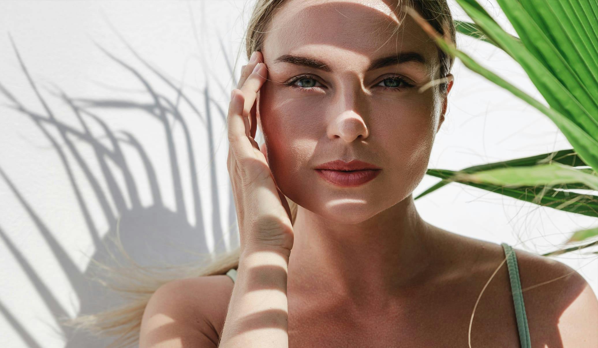 woman outside with shadows on her face from a plant