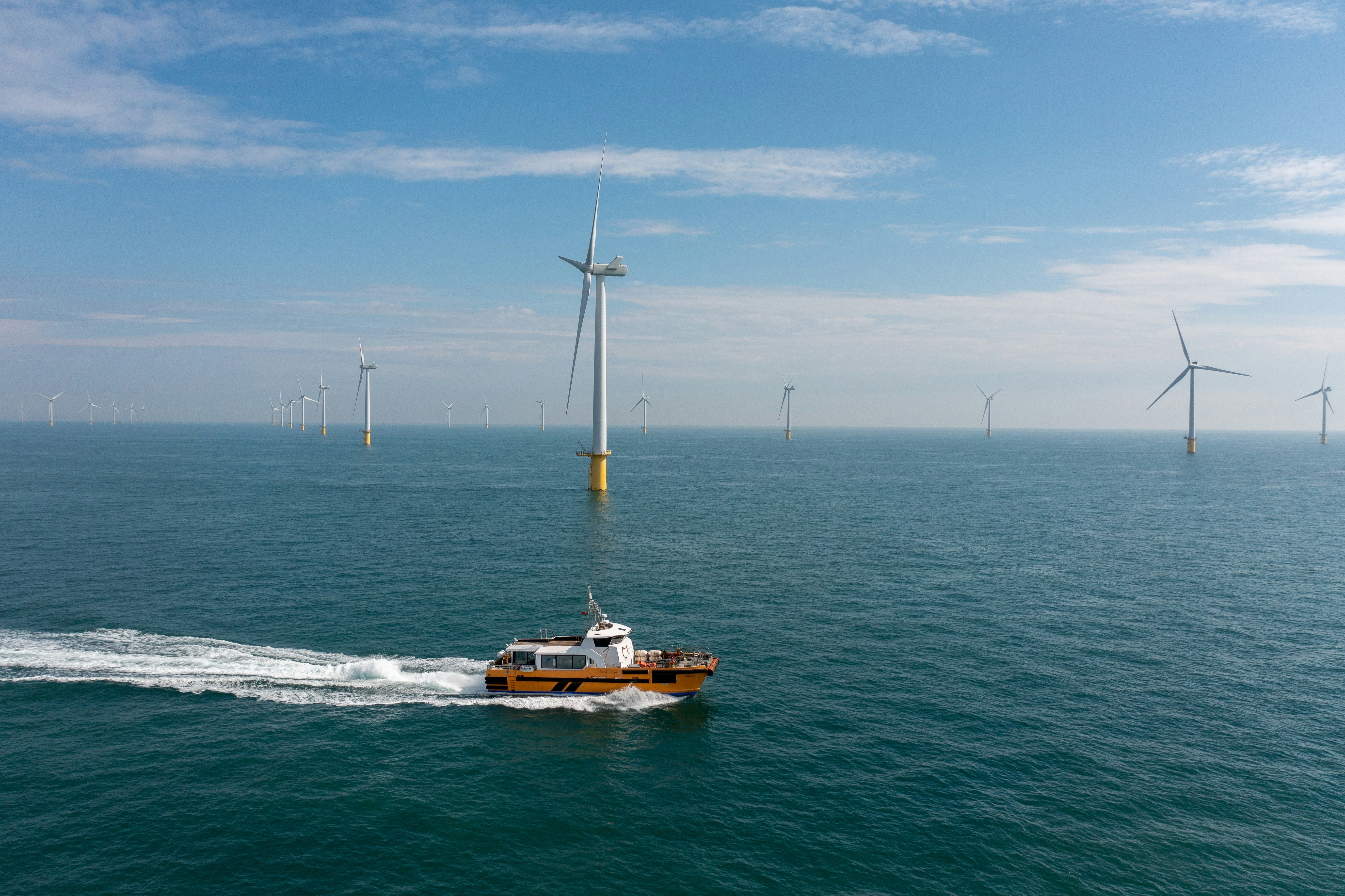 A boat moving in front of offshore wind turbines