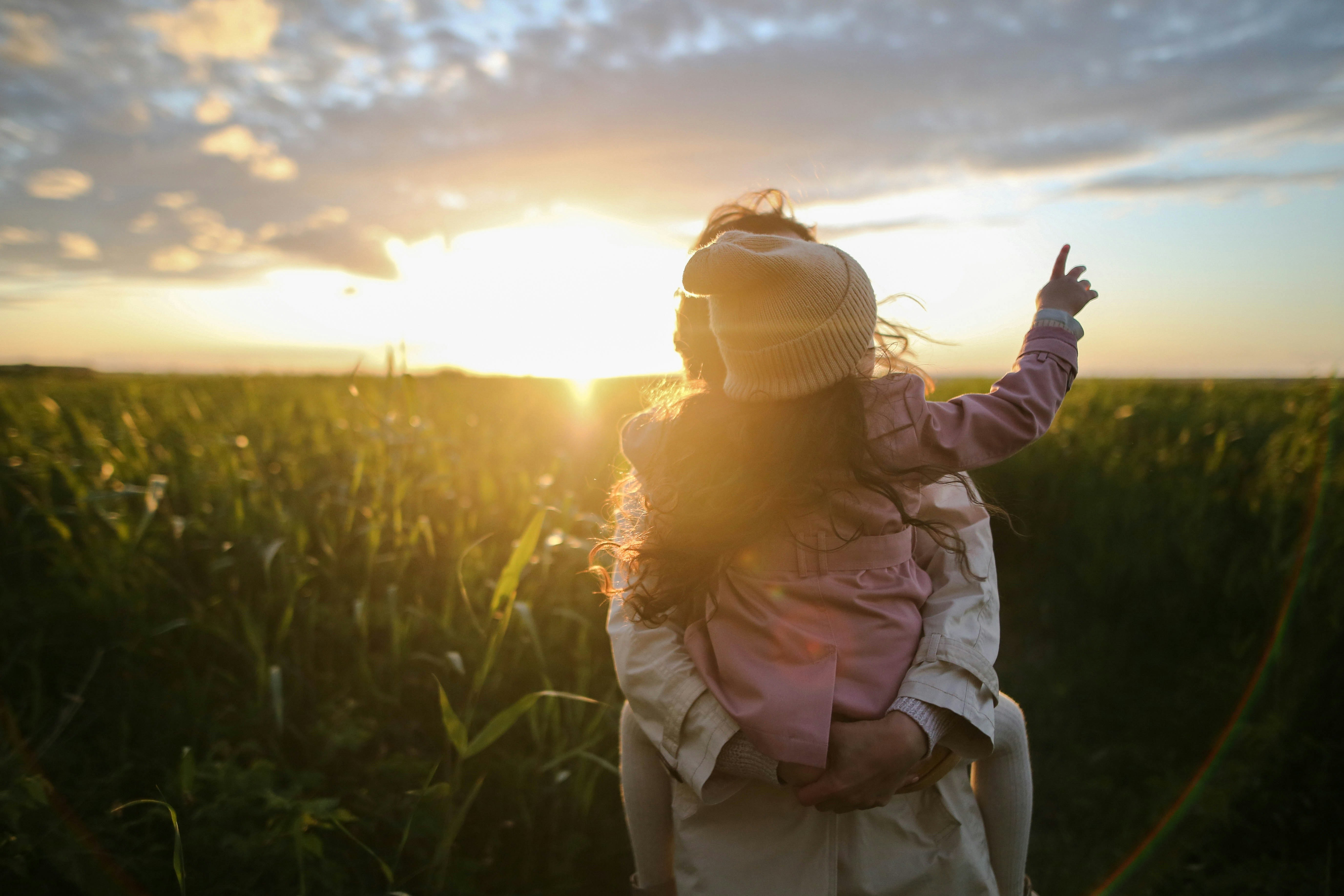 Parent and child in field at sunset