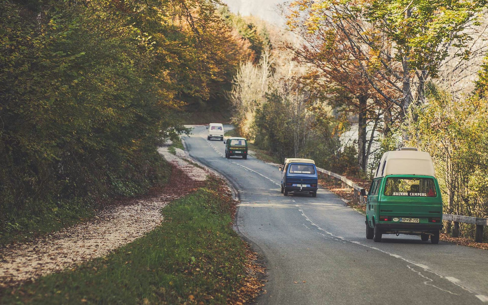 Four VW T3 Campervans from Balkan Campers on regional road at Bohinj Lake in Triglav National Park, Slovenia