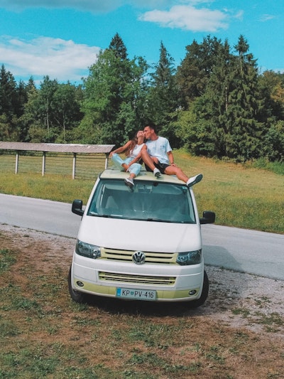 A couple from Portugal sitting on a roof of VW T5 camper van from Balkan Campers in Bled Lake, Slovenia