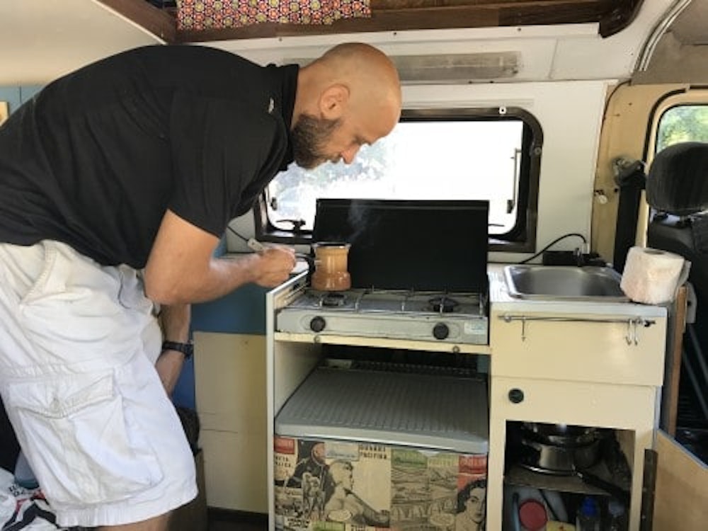 Man making coffee in vintage bus from Balkan Campers