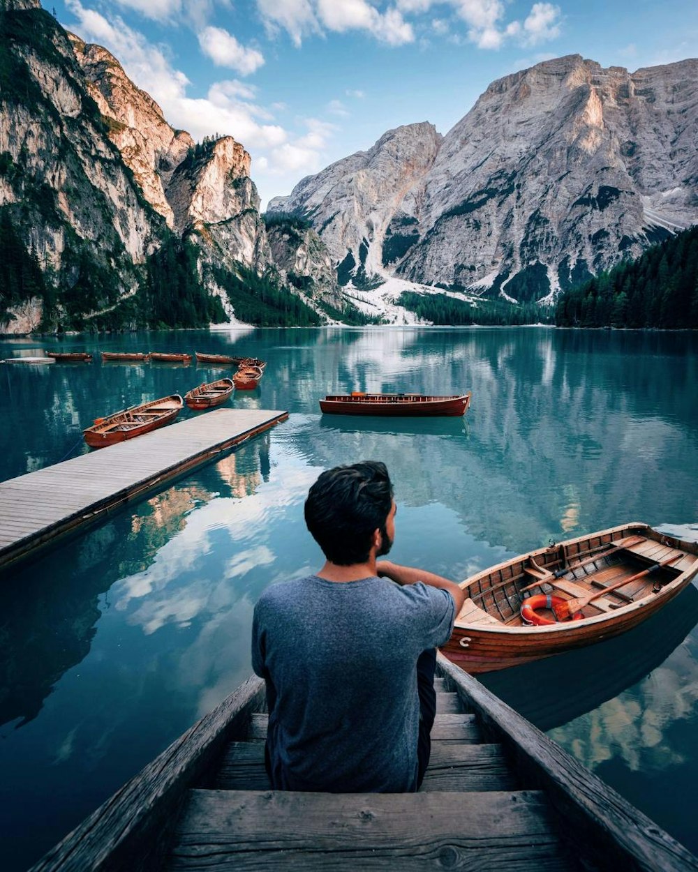 Lago Di Braies in Dolomites with a man sitting on wooden dock