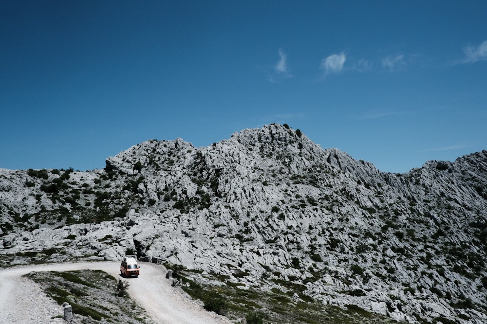 Orange VW T3 campervan on a Road on Velebit mountain