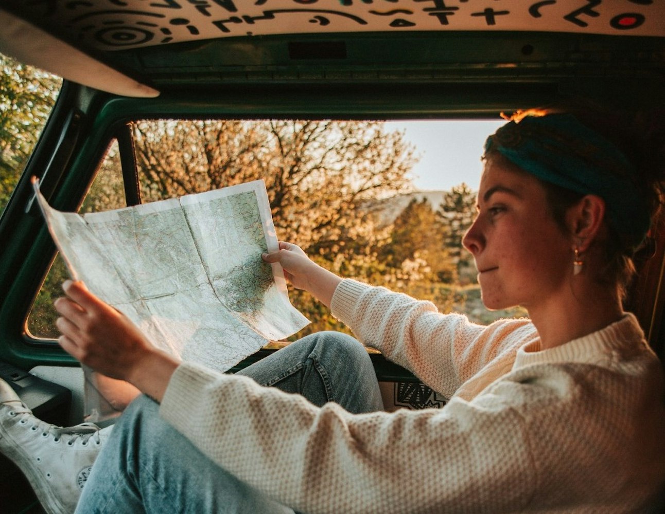 The girl is sitting in VW T3 van and checking the map
