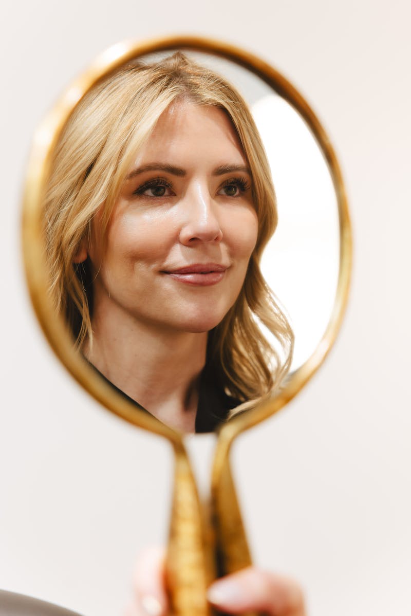 blonde woman looking into mirror
