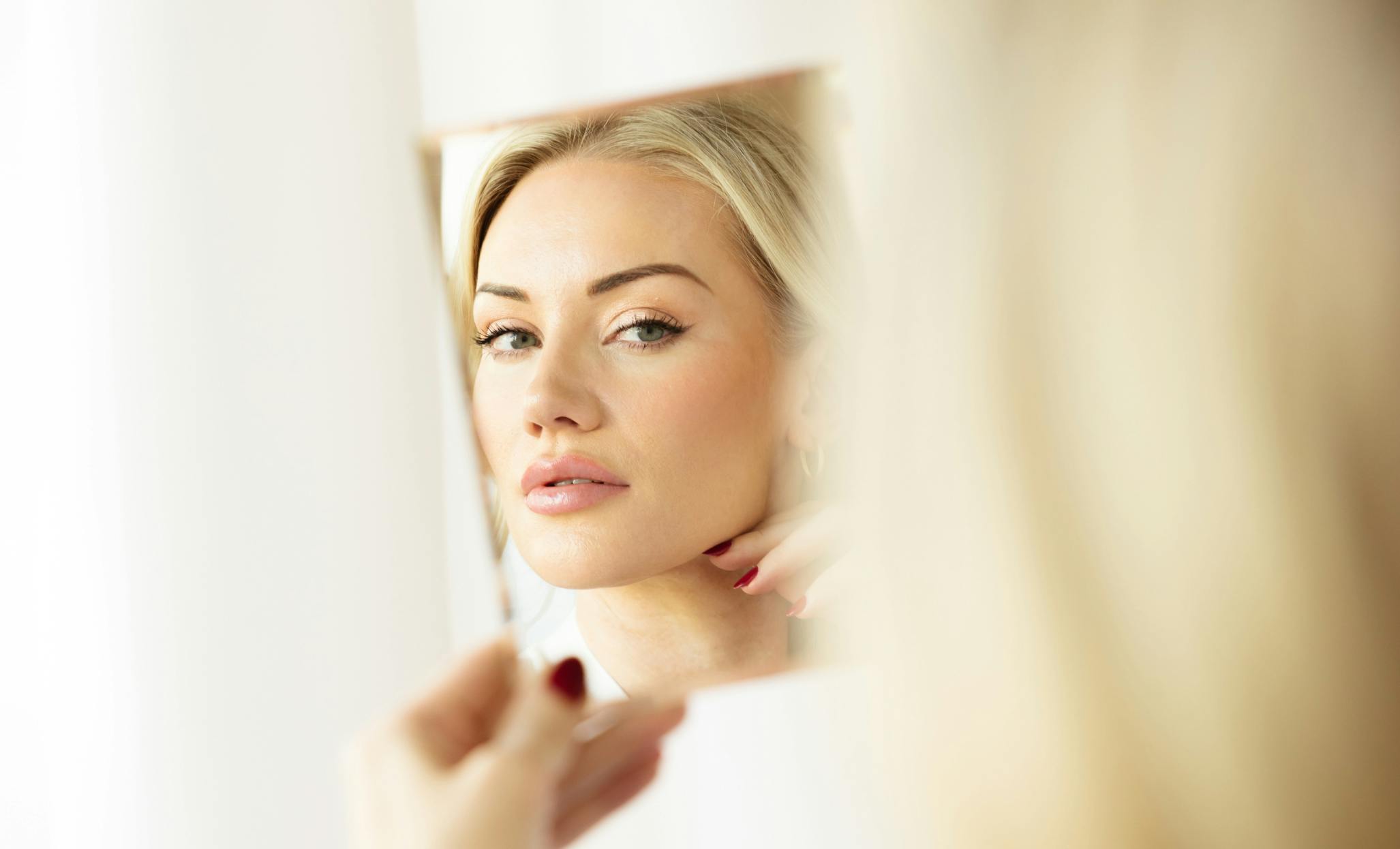 Woman looking at close-up in handheld mirror