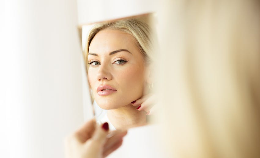 Woman looking at close-up in handheld mirror