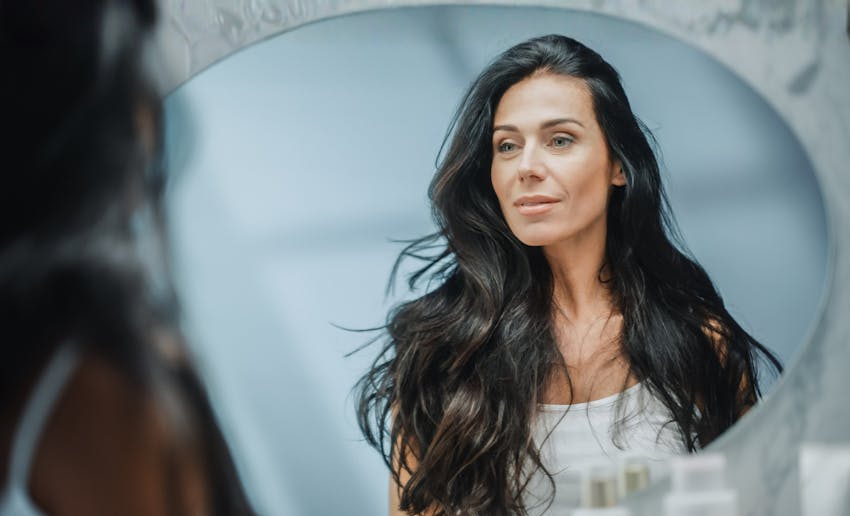 woman with black hair looking into mirror