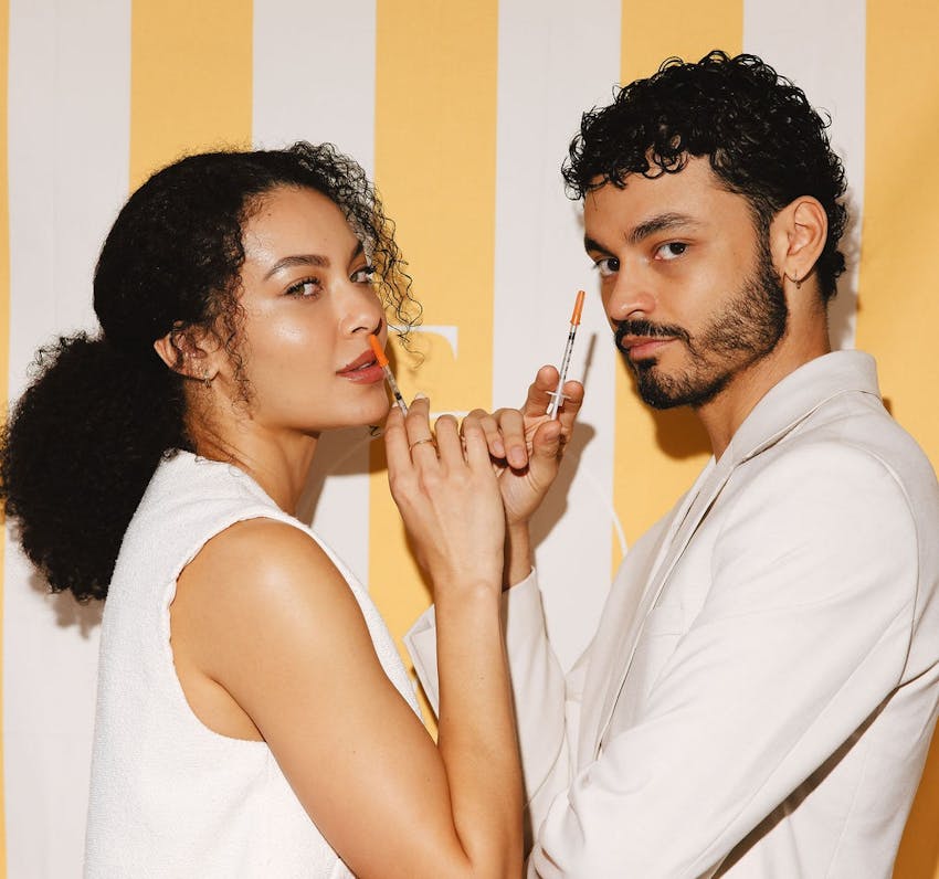 two people holding cosmetic syringes