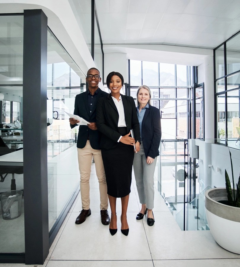 Group shot of three people in an white and open office.