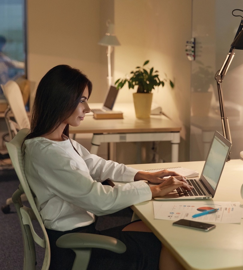 Image of a woman working on a laptop at a table