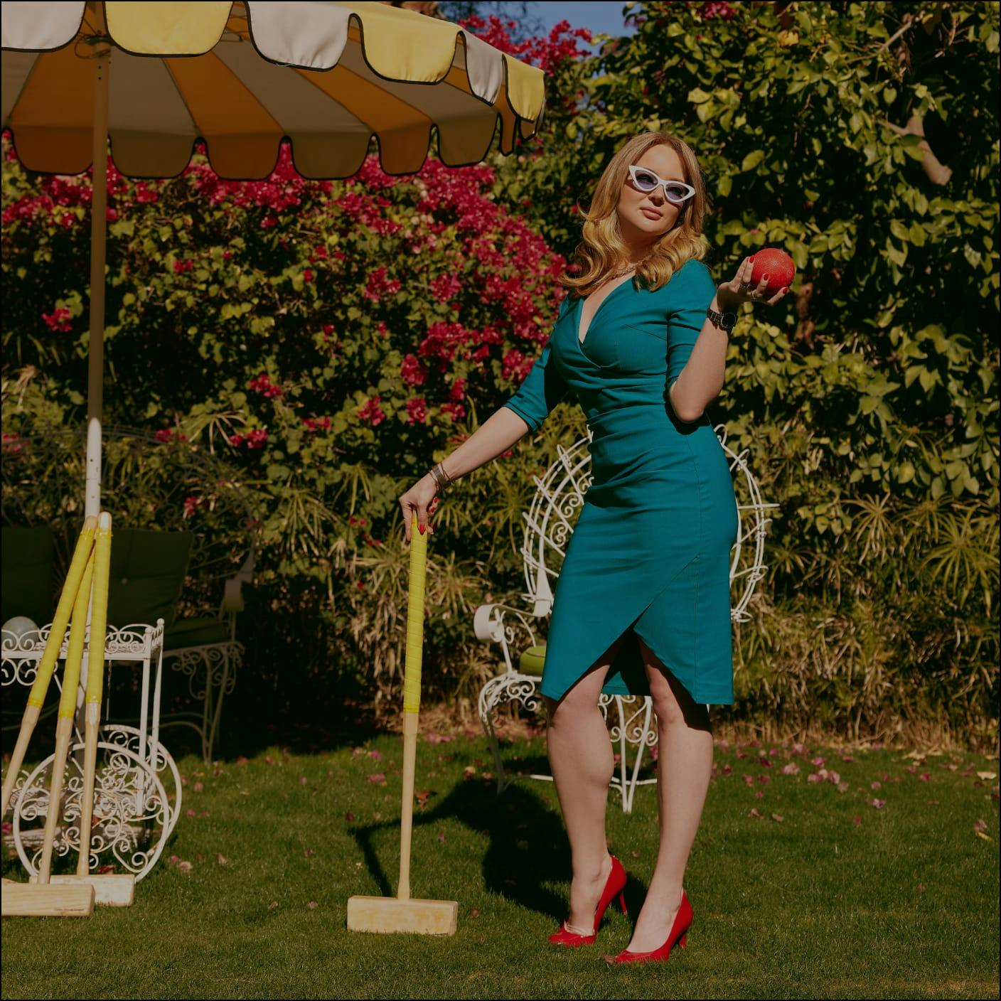 woman wearing a mid length teal dress playing croquet