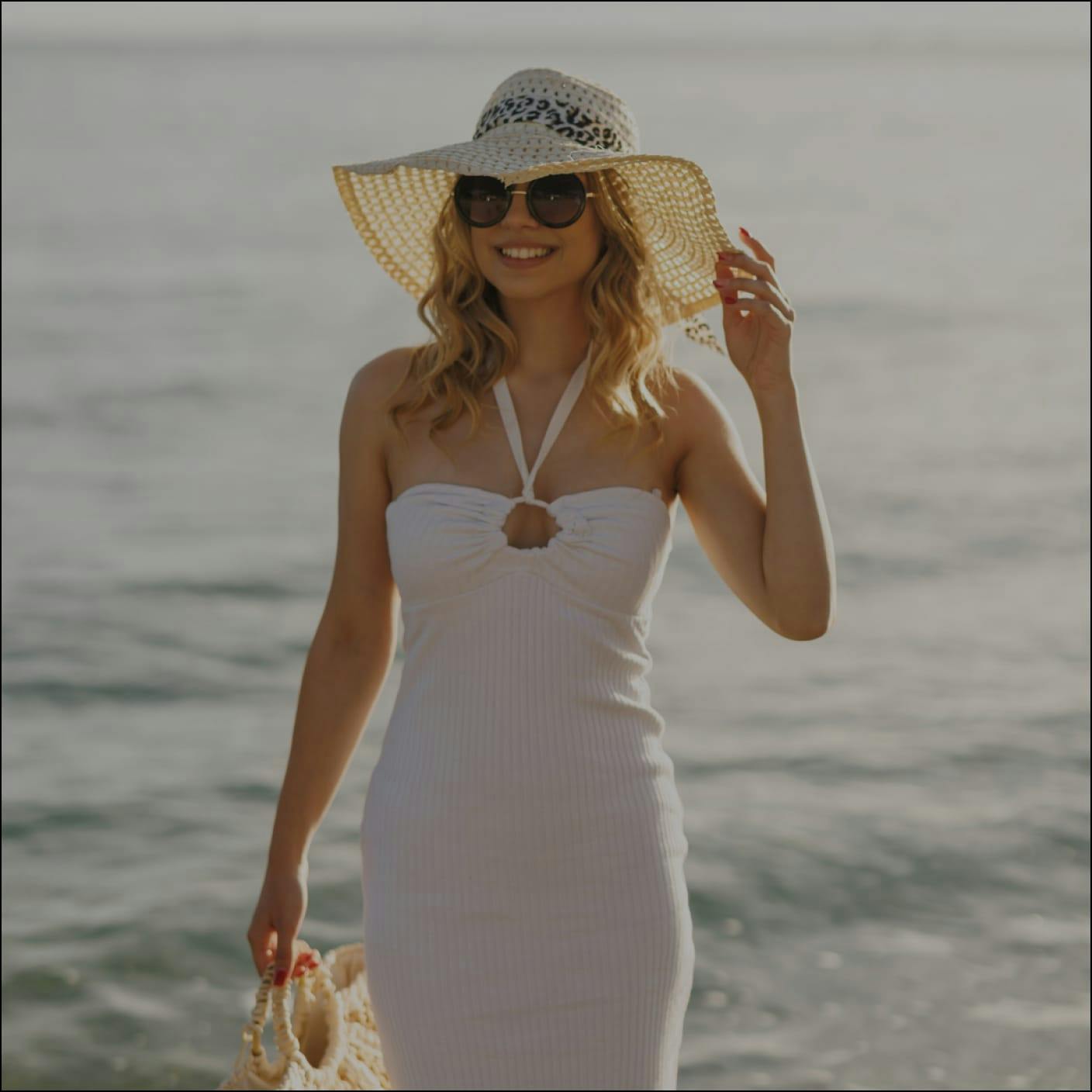 woman in a white dress and sunhat at the beach