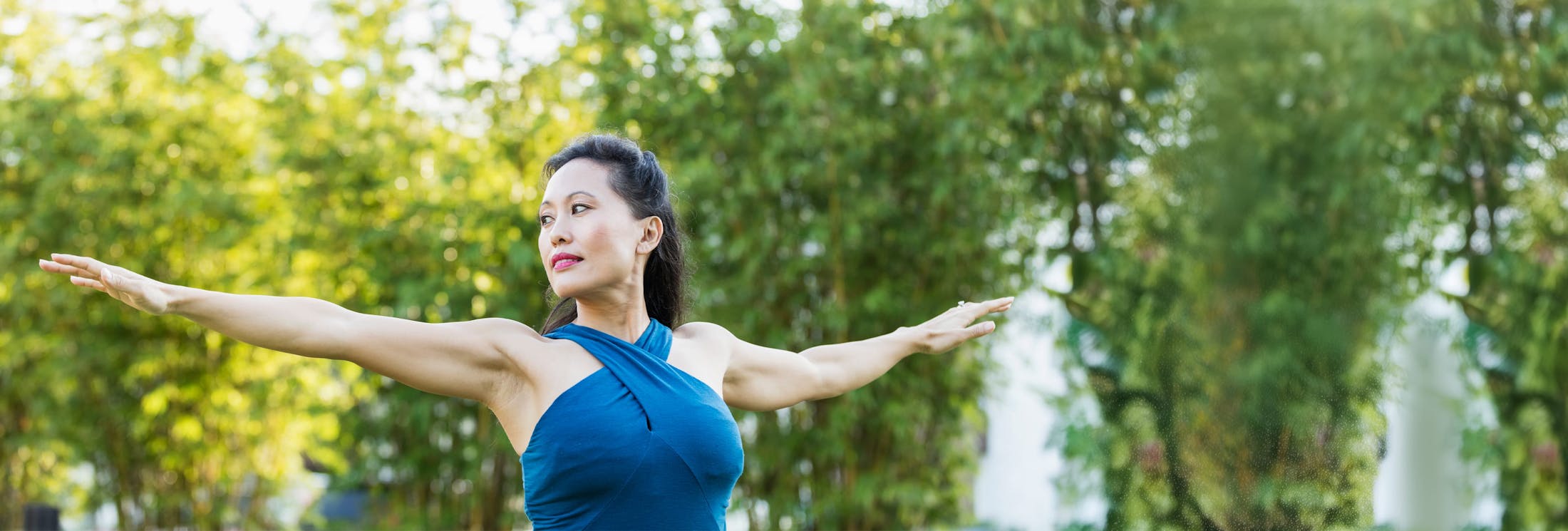 woman with her arms out with trees in background