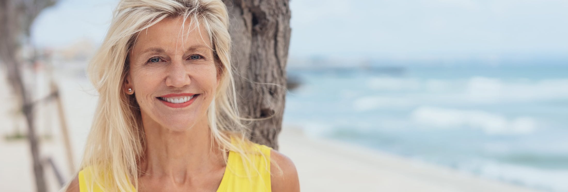 older woman smiling forward on a beach