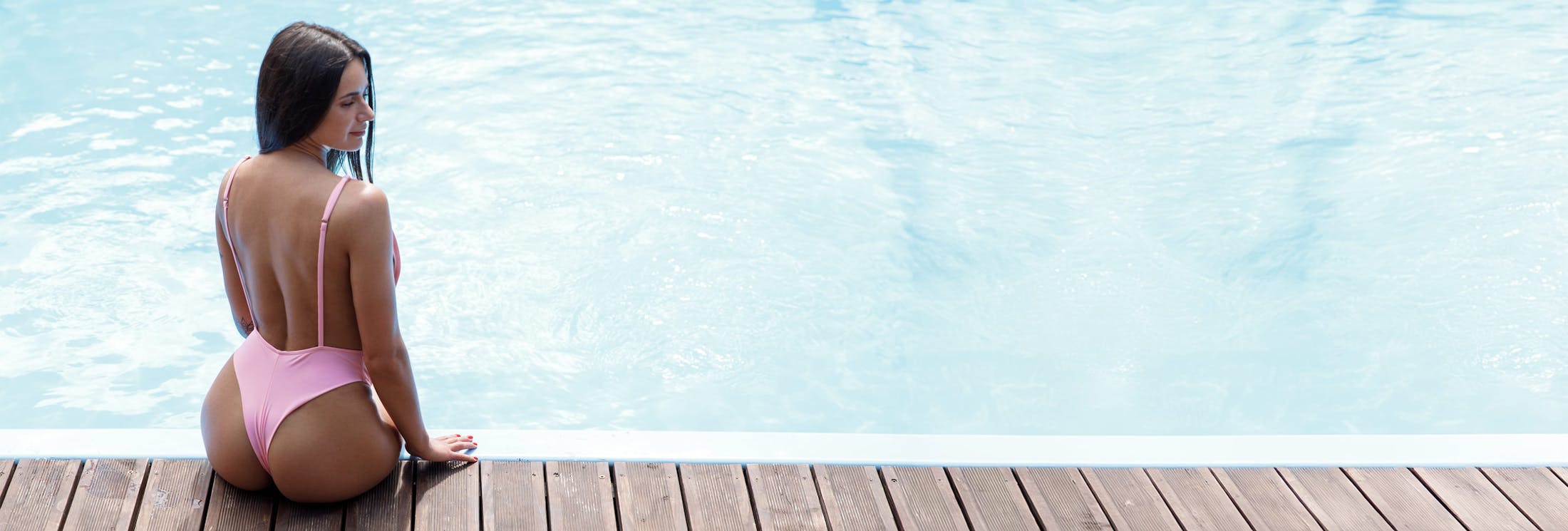 woman in pink swimsuit sitting on edge of pool