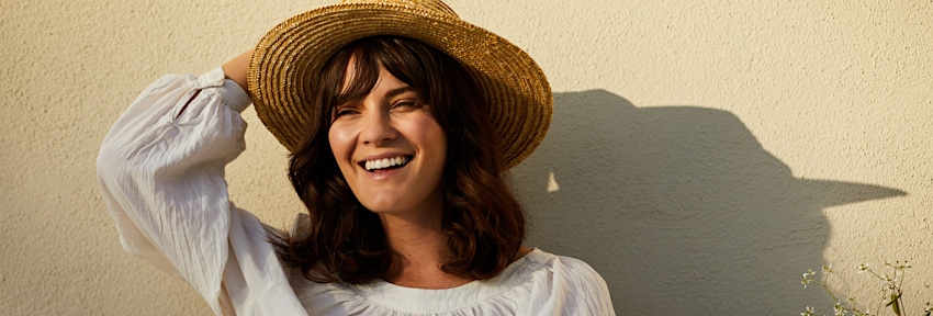 woman holding her hat on her head and smiling