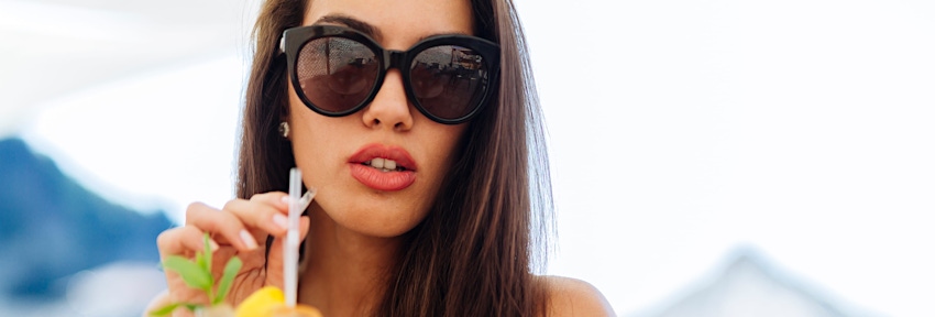 woman in sunglasses drinking a tropical drink