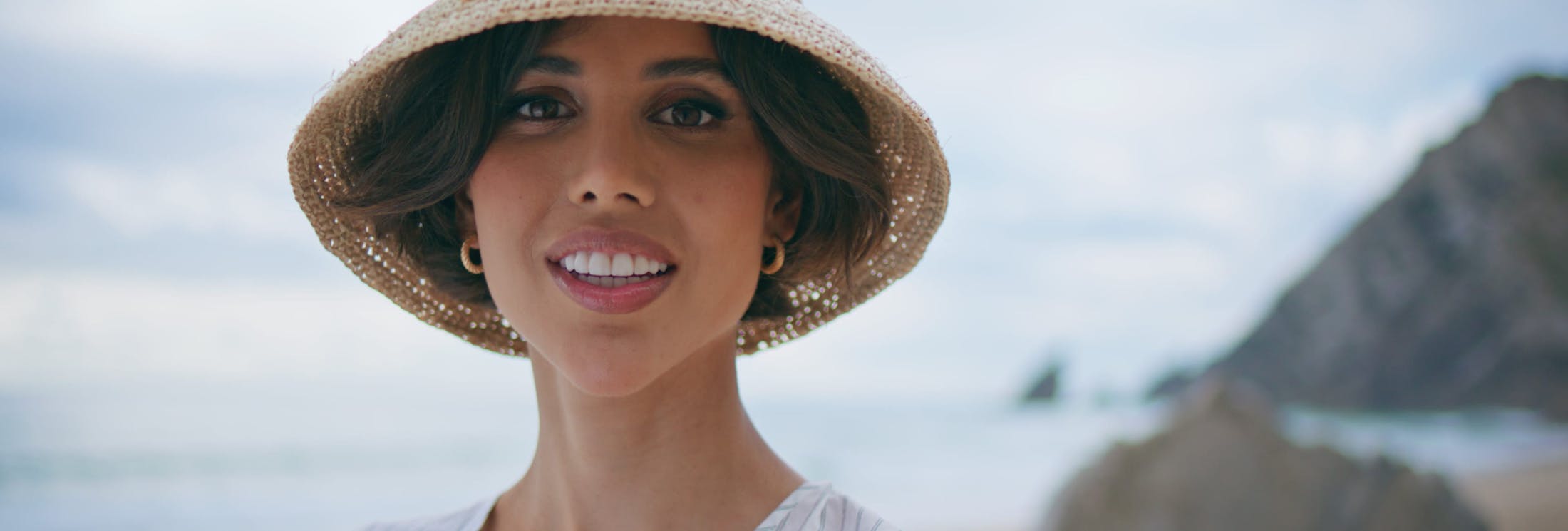 woman with short hair and a hat looking forward