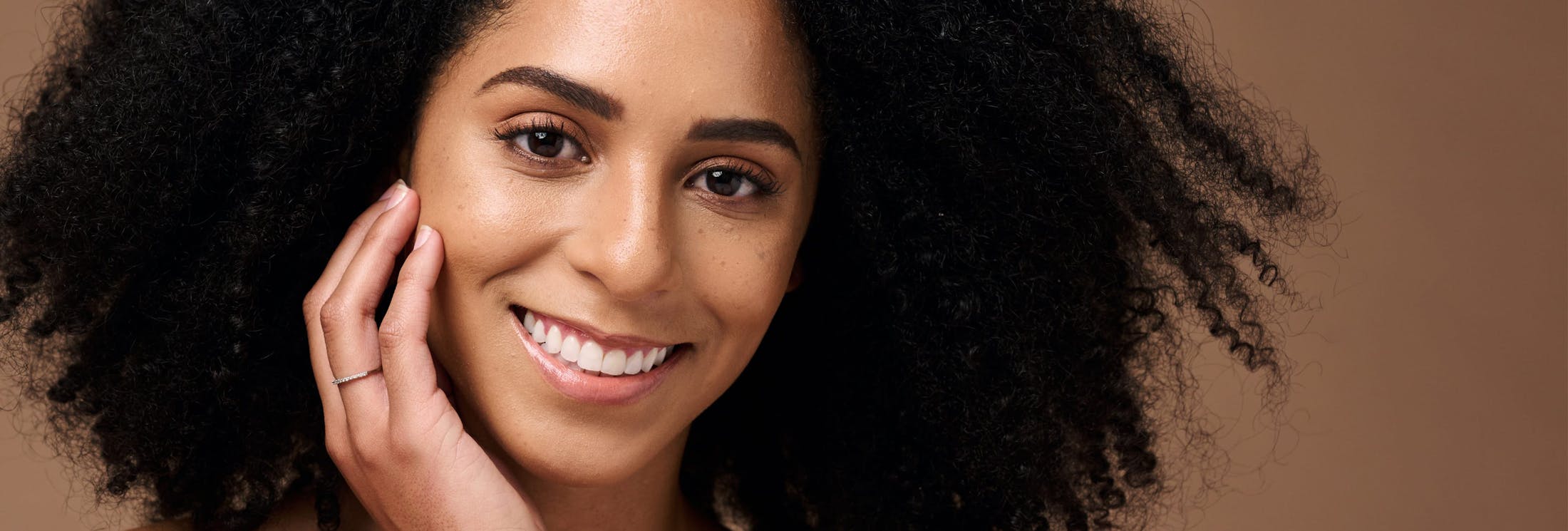 woman with afro touching her face