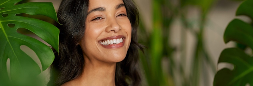 woman smiling with tropical leafs near her
