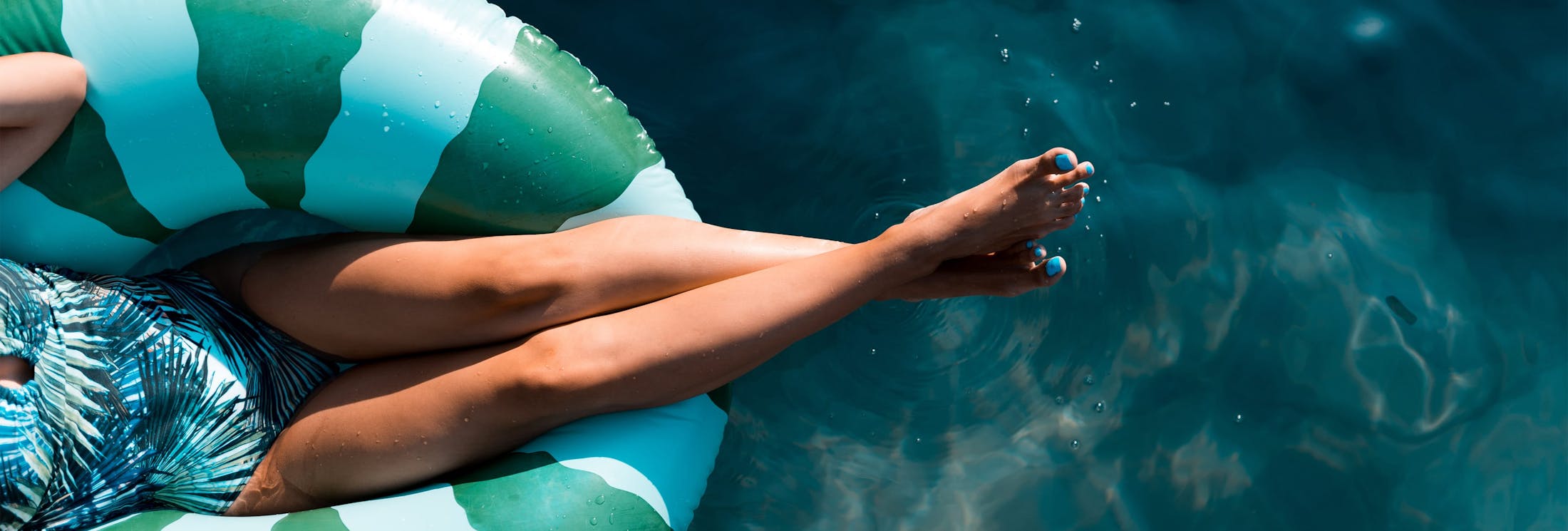 woman in a pool floaty with feet touching the water