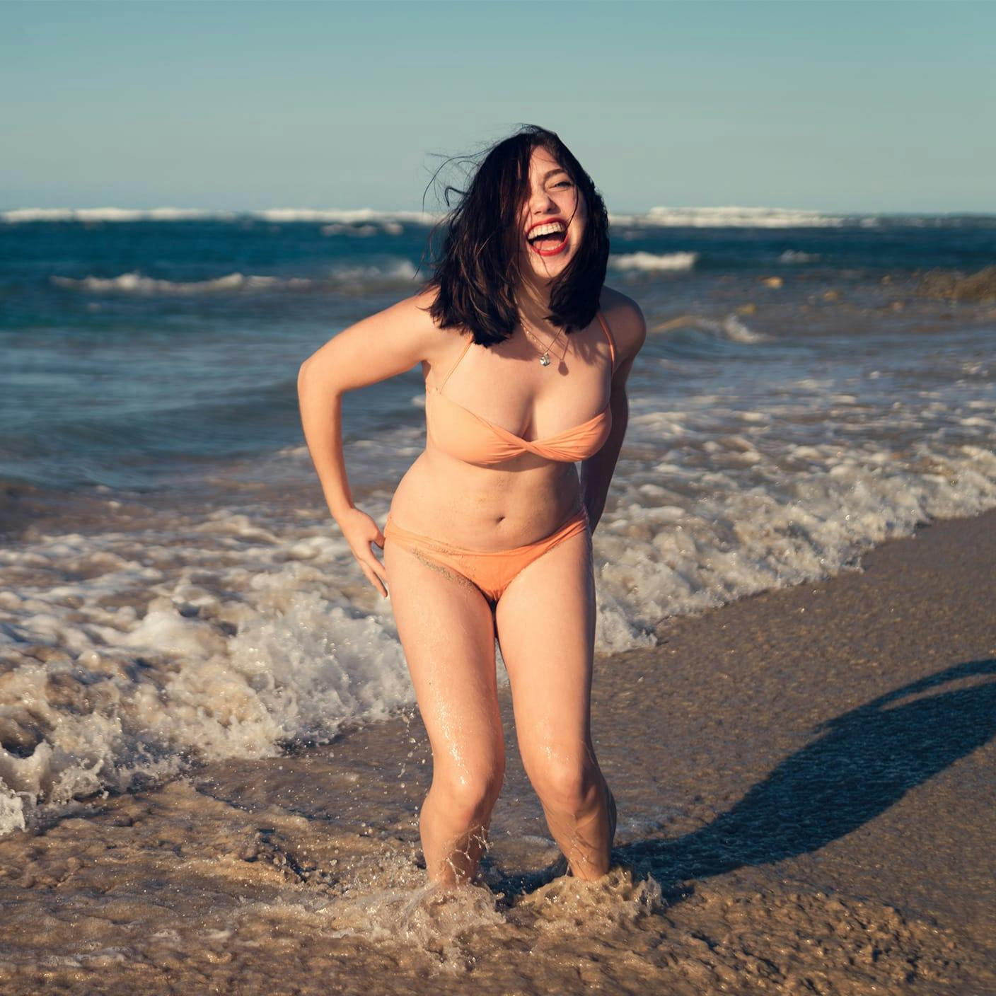 woman laughing at the beach in a bikini