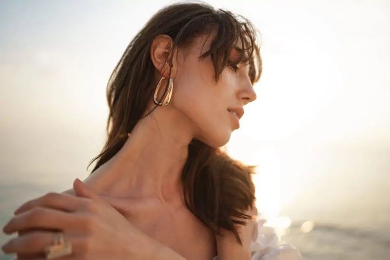 woman with long brown hair wearing gold hoop earrings