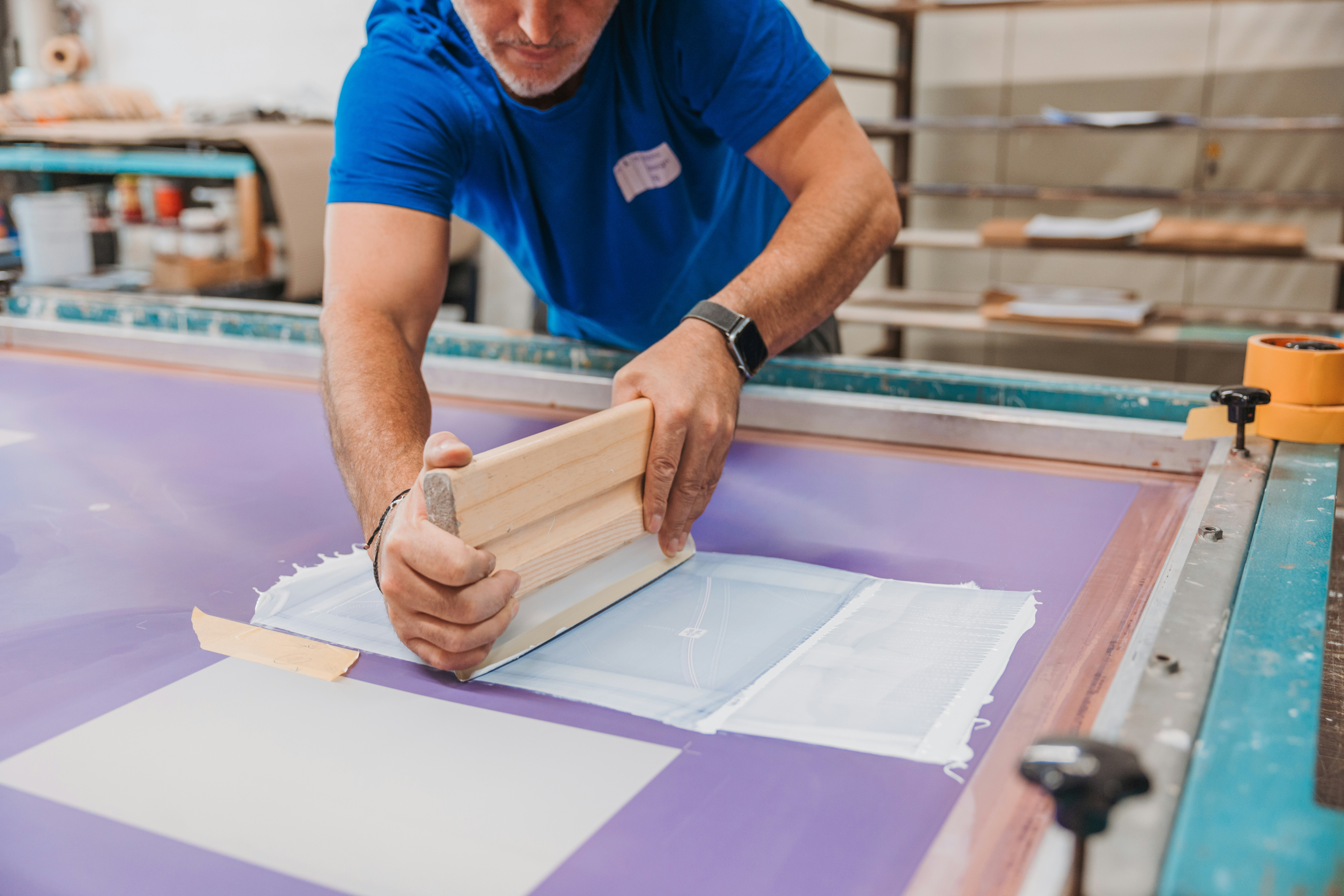 Der Emailleur druckt die Farbe durch das Sieb mit einem Rakel