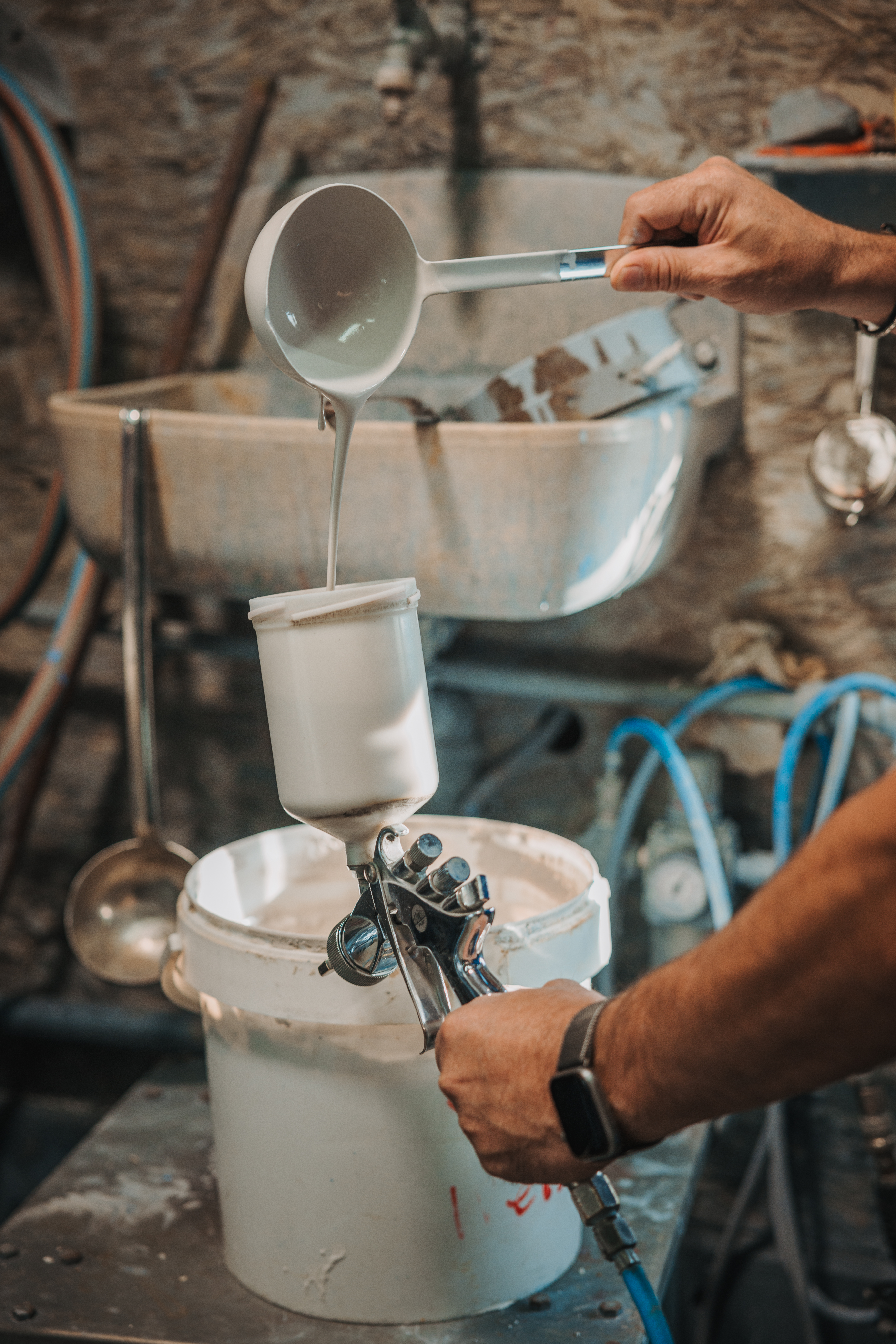 Der Emailleur füllt die Emaillemasse in den Behälter der Spritzdüse