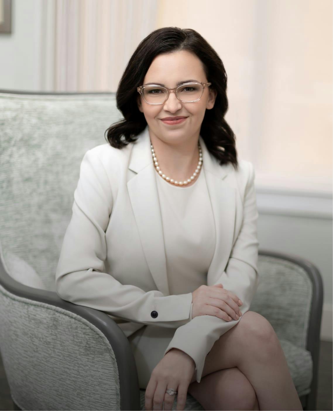 Woman sitting in a chair with a white jacket on