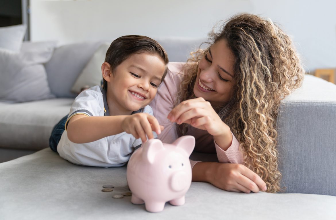 mother and son putting coins into piggy bank 