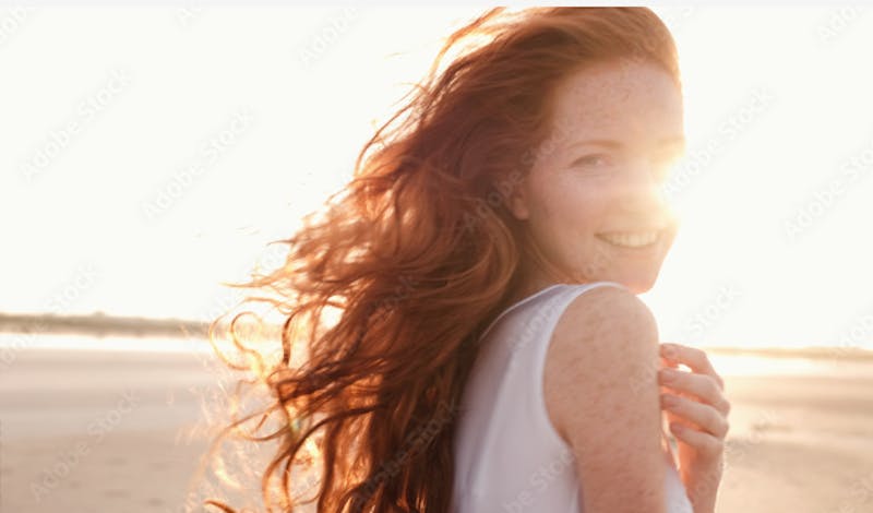 Woman with red hair in front of a sunset