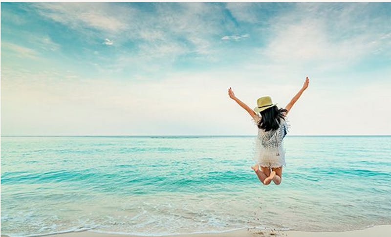 Woman jumping in front of the ocean