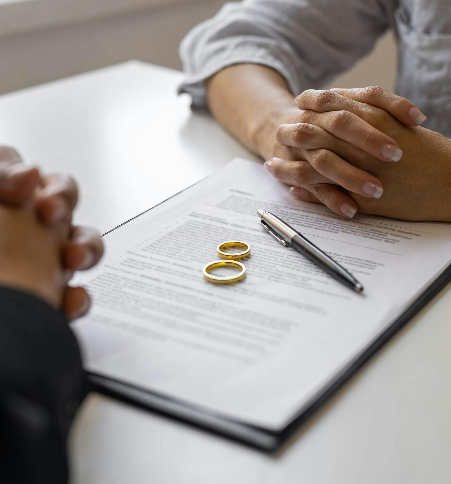 hands crossed on table with wedding rings in the center