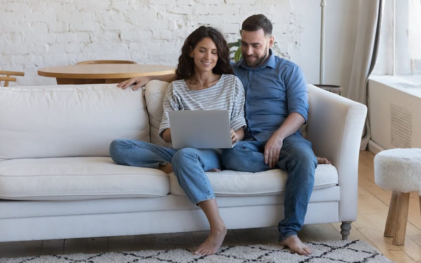 couple on couch looking at laptop