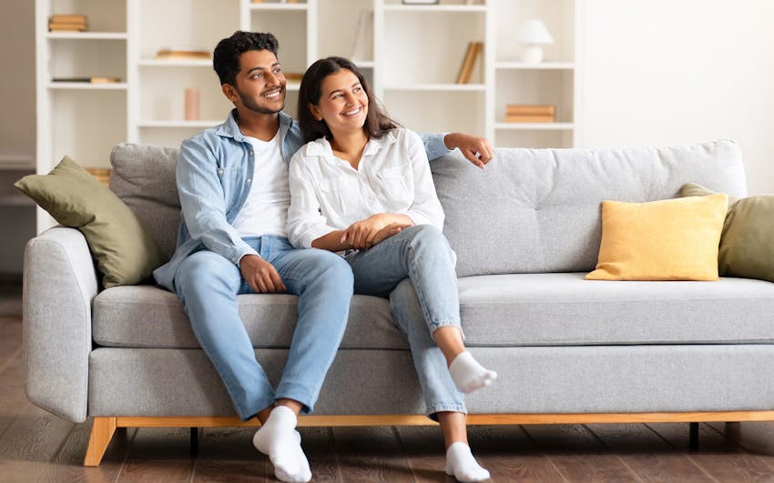 couple sitting on couch smiling looking to the right