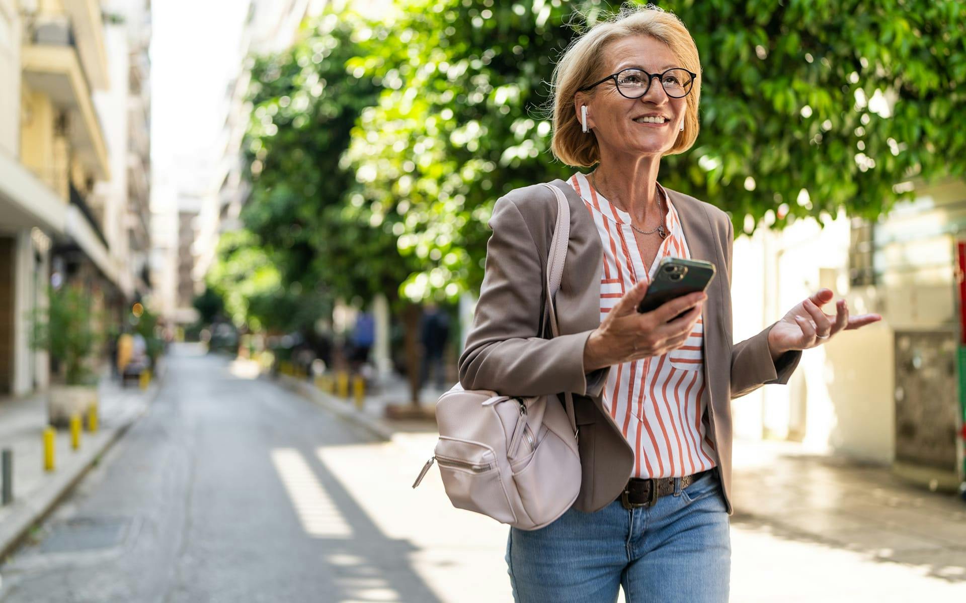 woman on phone walking in alleyway smiling
