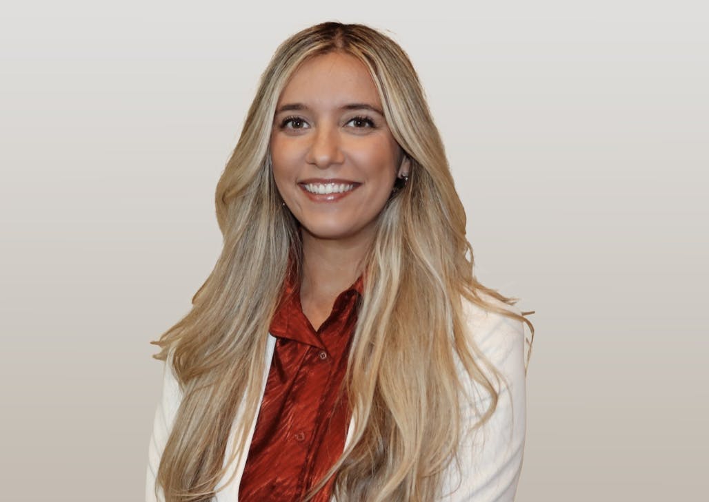 Blonde woman in a red top and white jacket
