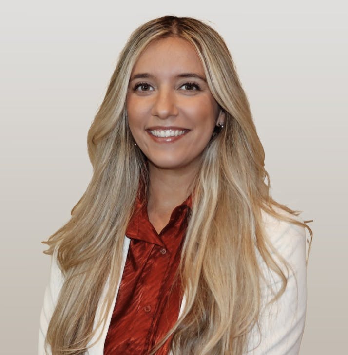 Blonde woman in a red top and white jacket